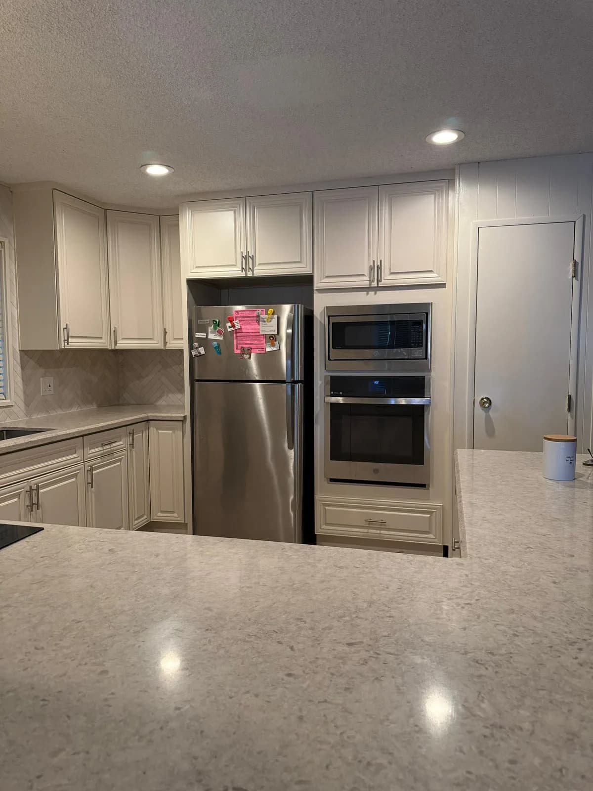 Appliance wall with built-in microwave and wall oven in white raised-panel cabinetry