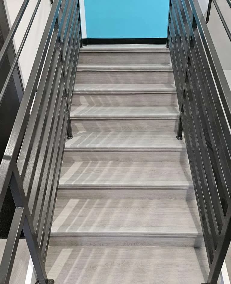 Renovated commercial staircase with metal railings and gray wood-look treads