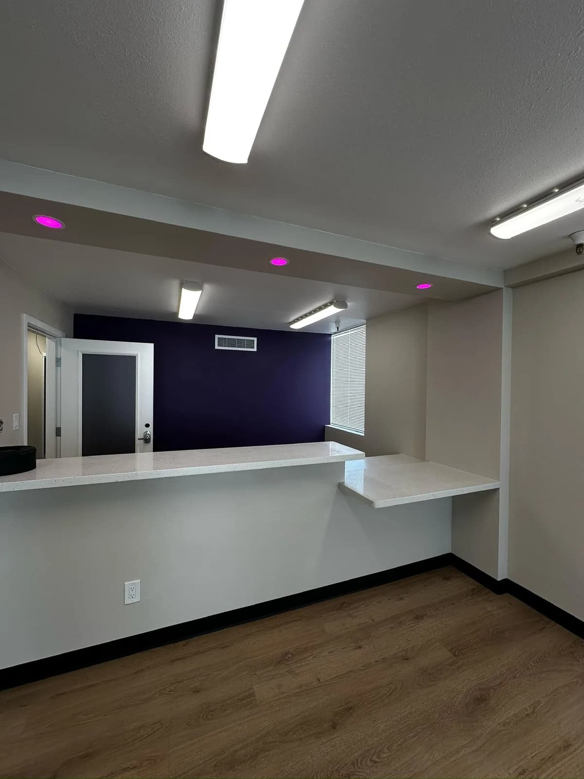 Commercial reception area with built-in white desk and accent lighting