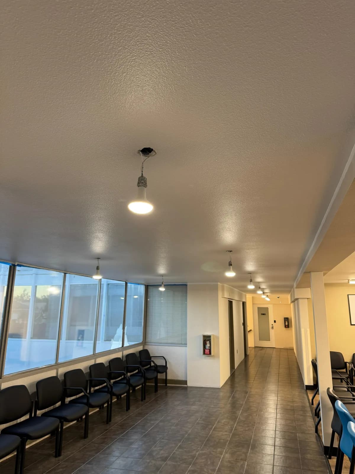 Commercial waiting area with rows of chairs and pendant lighting