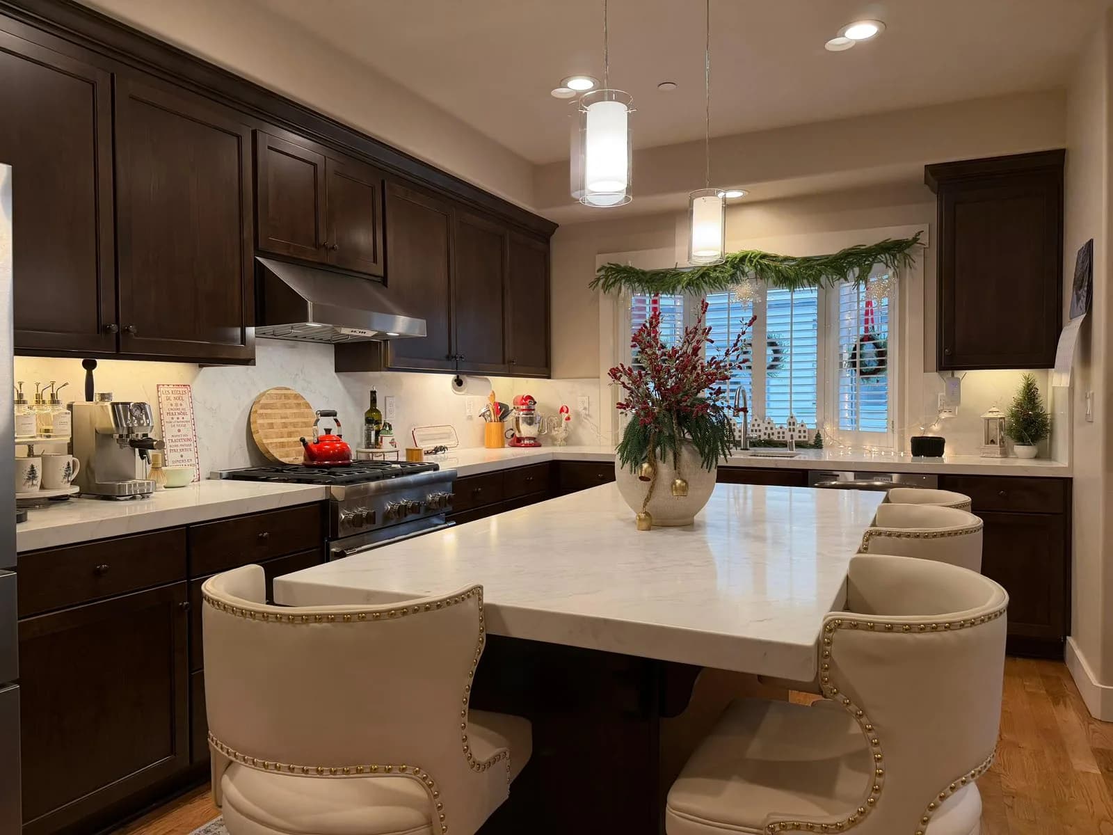 Marble-look quartz island with seating in an espresso kitchen with pendant lighting
