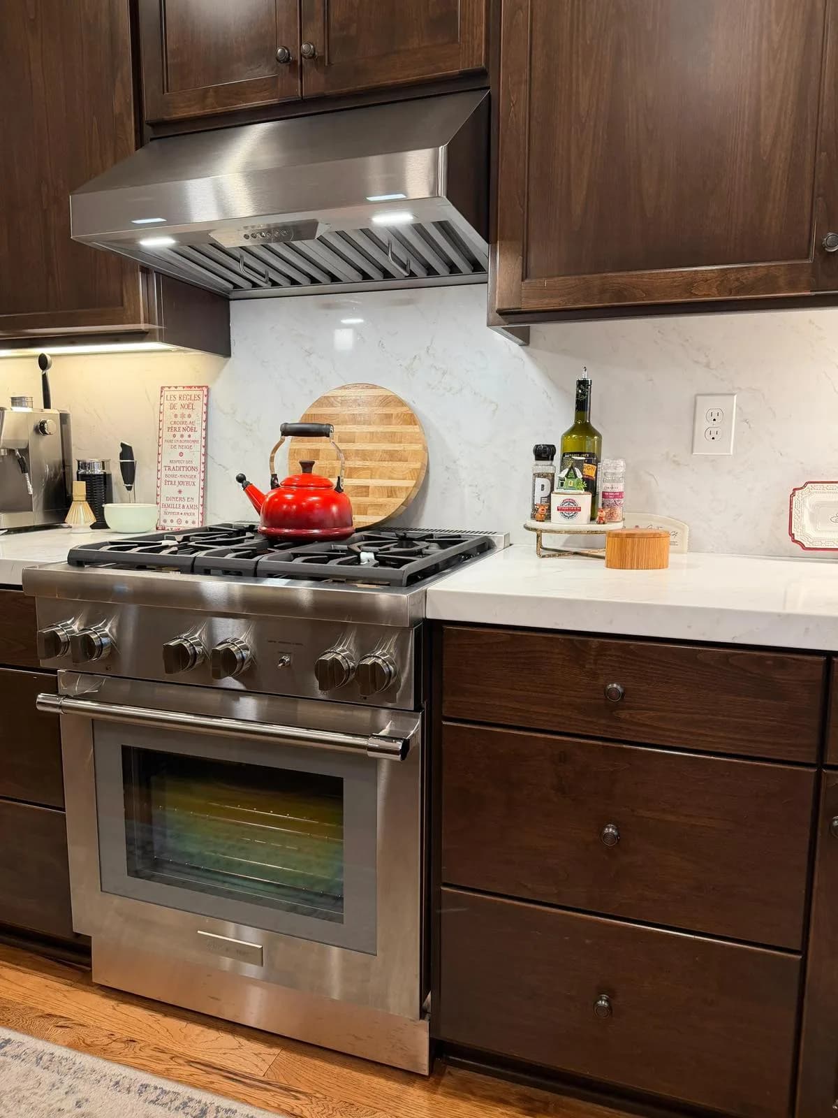 Stainless professional-style gas range with marble-look quartz backsplash and espresso cabinets