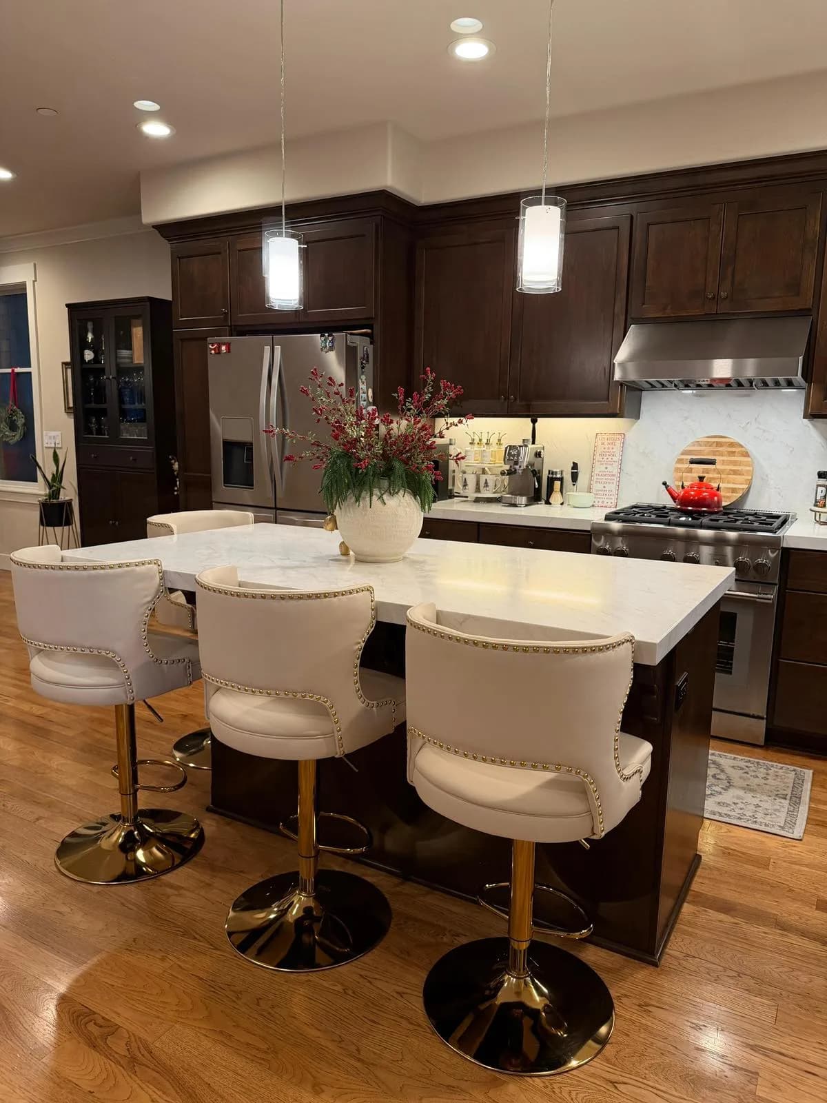 Pendant lights over a quartz island with seating in an espresso kitchen