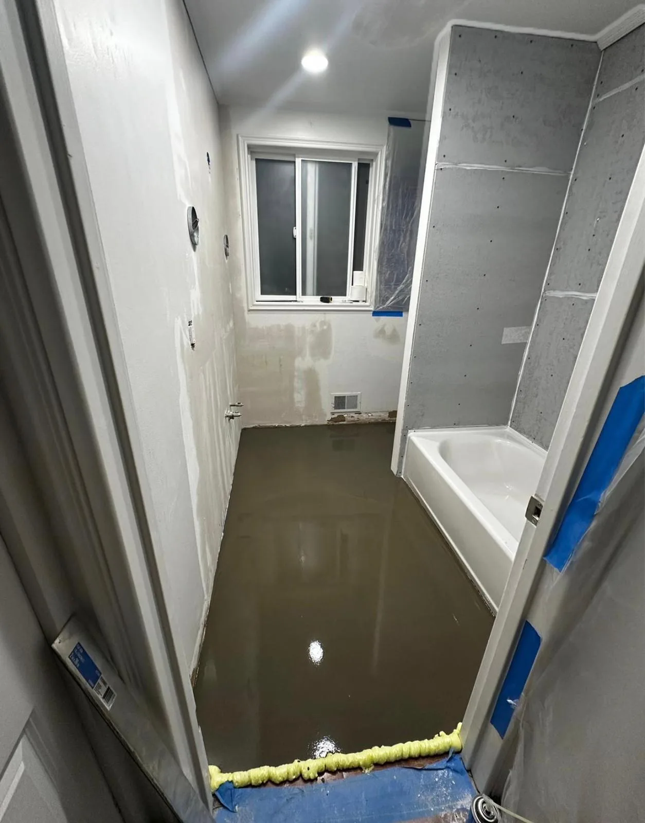 Bathroom floor prep during remodel — poured leveling underlayment with cement-board backer on the tub surround