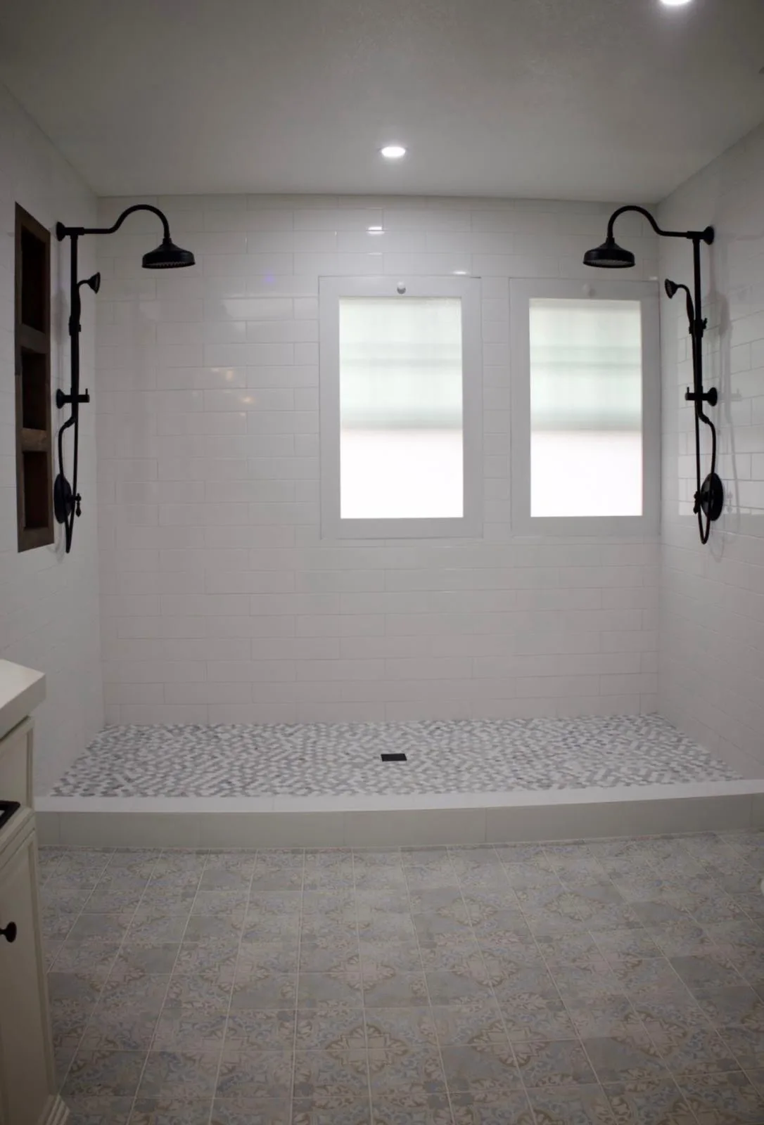 Walk-in shower with dual black rainfall shower heads and white subway tile