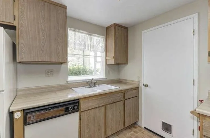 Kitchen sink wall before remodel with oak cabinets and tan laminate counters