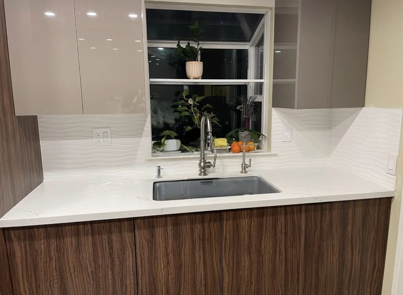 Remodeled kitchen with high-gloss taupe upper cabinets and wood-grain lowers under a garden window
